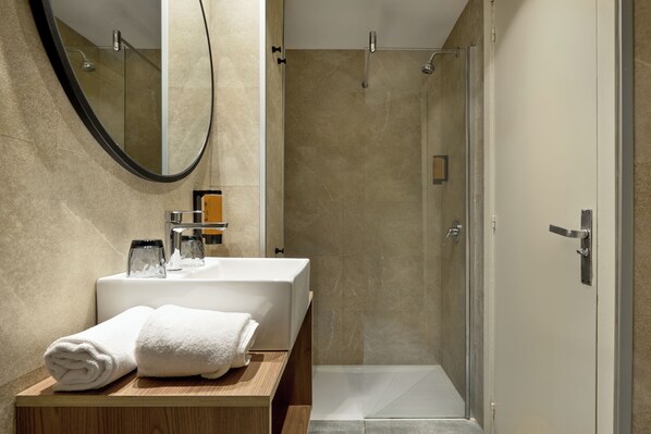 A modern bathroom with a large mirror, a sink, and a shower.