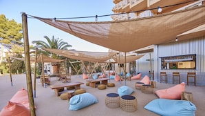An outdoor seating area with tables and chairs, shaded by large canopies, and a bar area in the background. - tent Palmanova (Calvia)