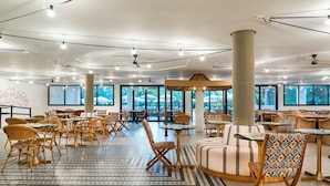 A spacious indoor area with multiple seating arrangements, including tables and chairs, and large windows providing natural light. - tent Palmanova (Calvia)