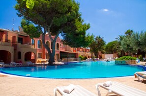 A swimming pool surrounded by lounge chairs and a building with arched windows.