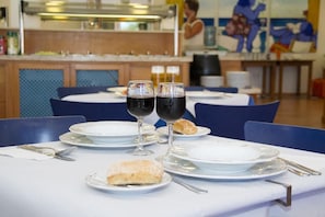 A dining table set with plates, glasses, and cutlery, with a mural in the background.