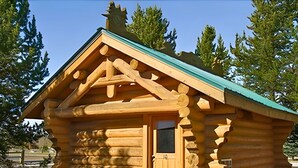 Une cabane en rondins avec une porte en bois et un petit porche.