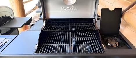 A Noxall grill with a black exterior, four control knobs, and a gas burner.