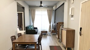 A dining area with a wooden table and chairs, a sofa, a television, and a cabinet. - Seaview Apartment (Langkawi)