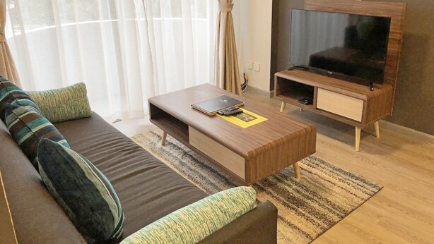 A modern living room with a sofa, coffee table, and TV stand. - Seaview Apartment (Langkawi)