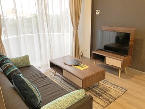 A modern living room with a sofa, coffee table, and TV stand. - Seaview Apartment (Langkawi)