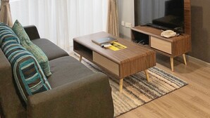 A living room with a sofa, a coffee table, a TV, and an air conditioning unit. - Seaview Apartment (Langkawi)