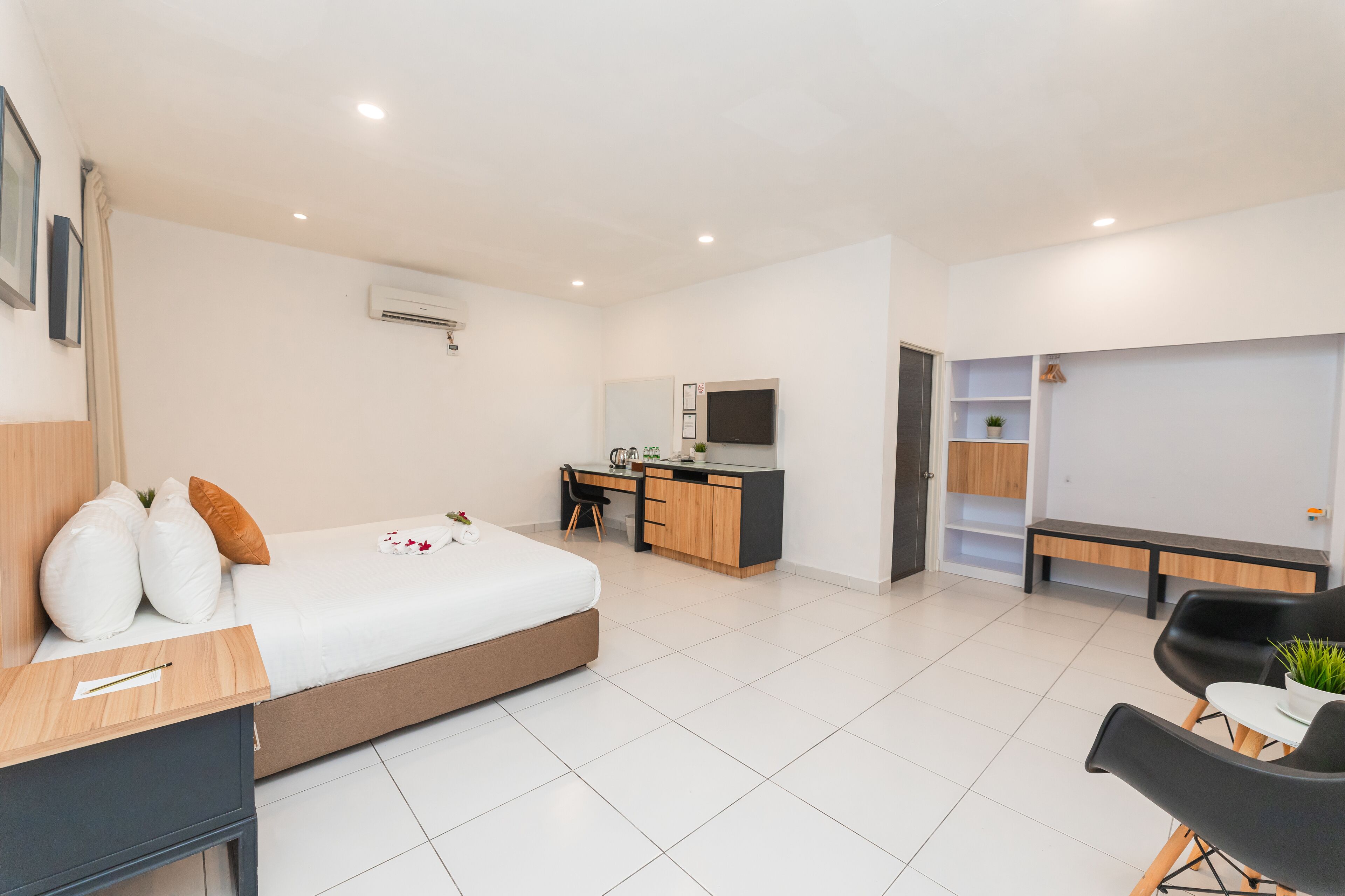 A modern hotel room with a bed, desk, and seating area.