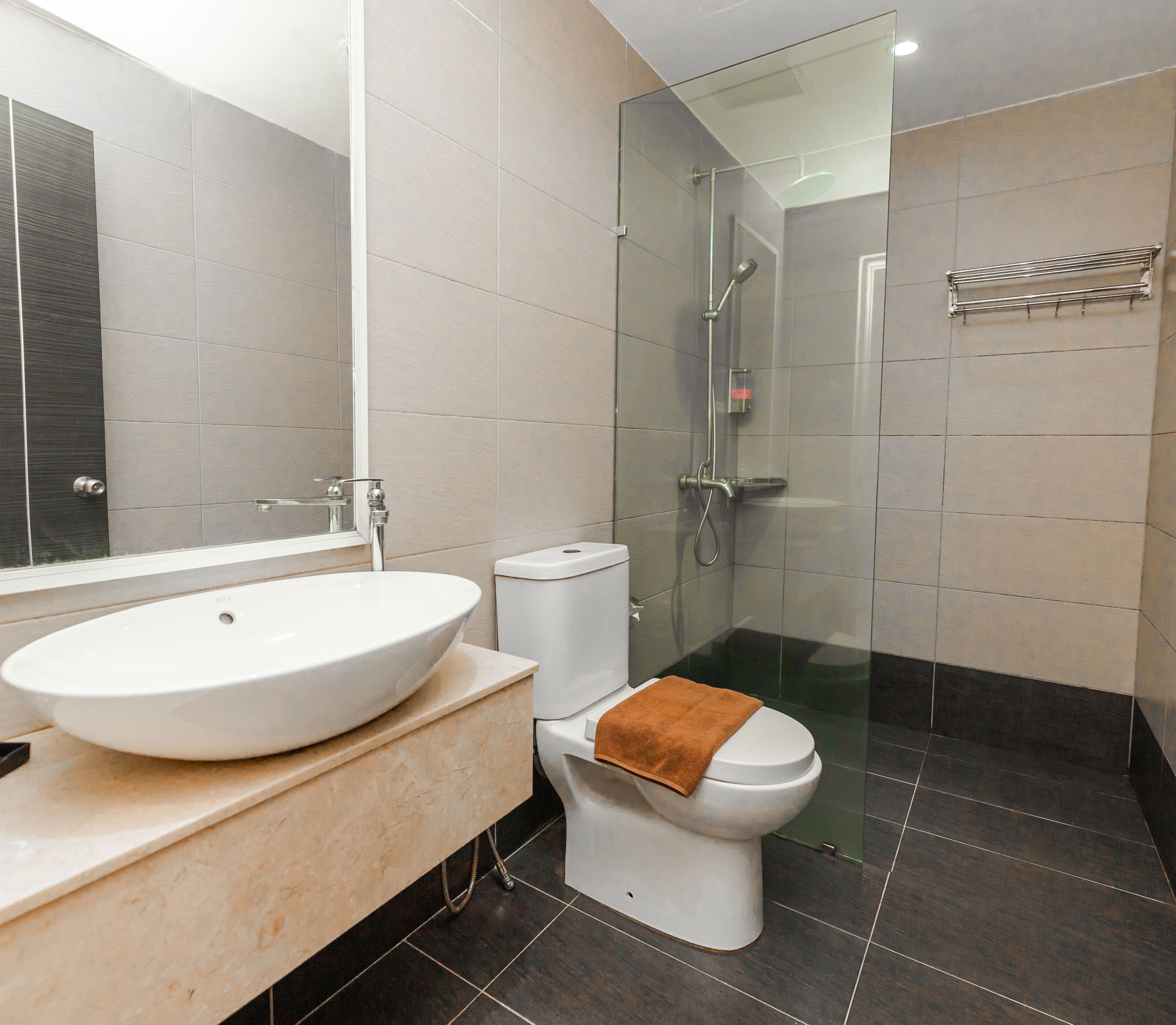 A modern bathroom with a large white sink, a toilet with a towel, and a glass-enclosed shower area.