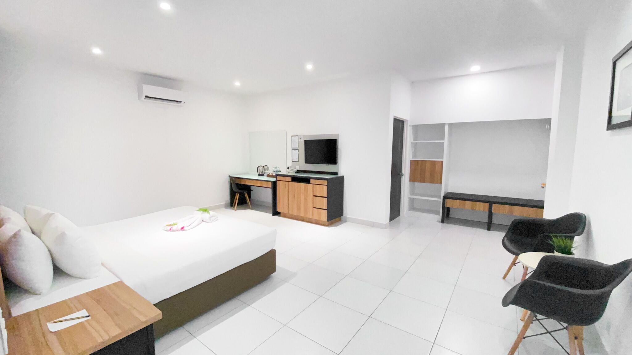 A modern hotel room with a bed, a desk, a chair, a TV, and a wardrobe.