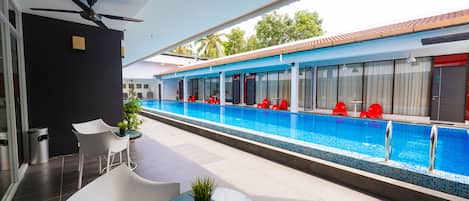 Un hotel moderno con piscina, mobiliario exterior y ventilador de techo.