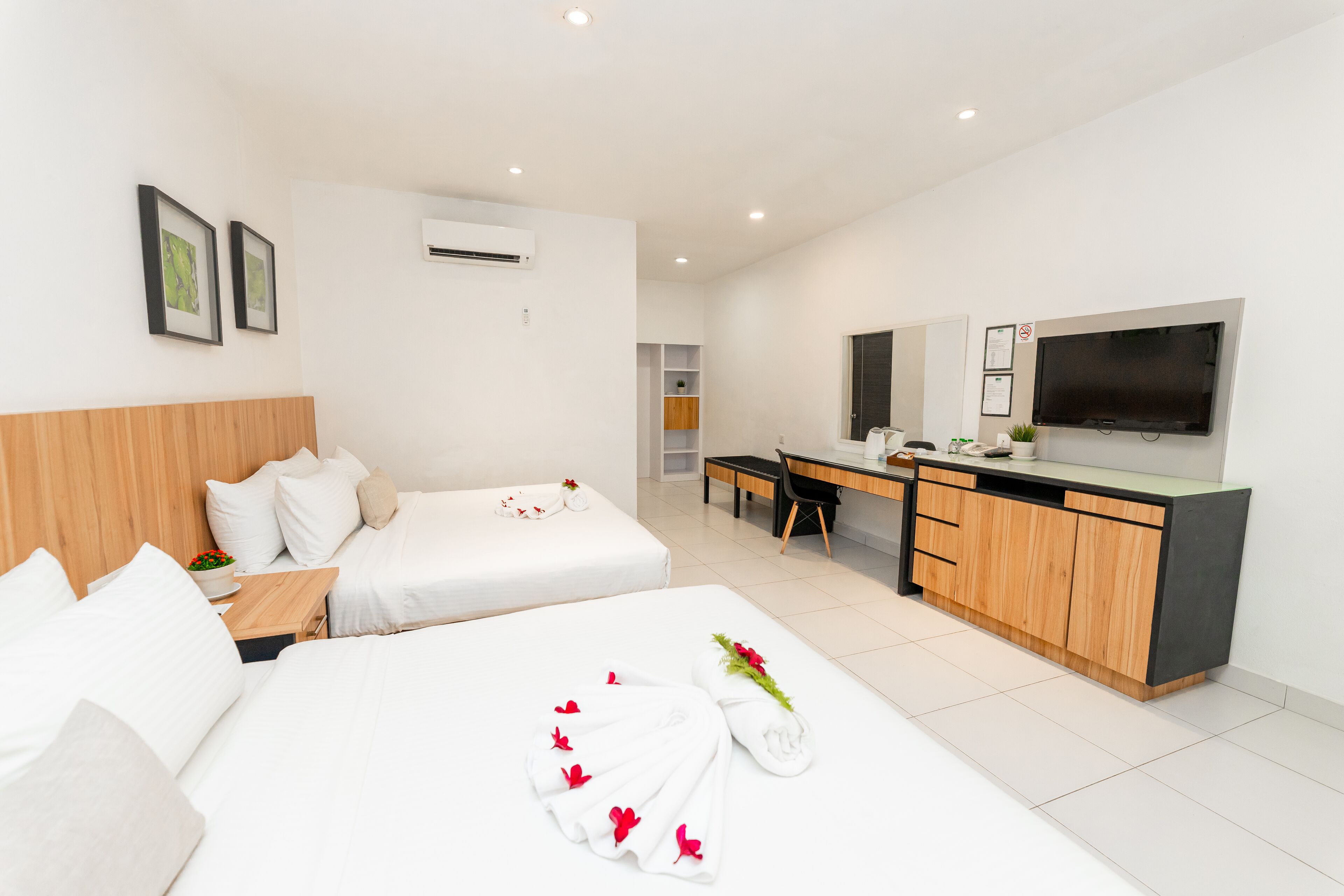 A hotel room with two beds, a desk, a TV, and a minibar.