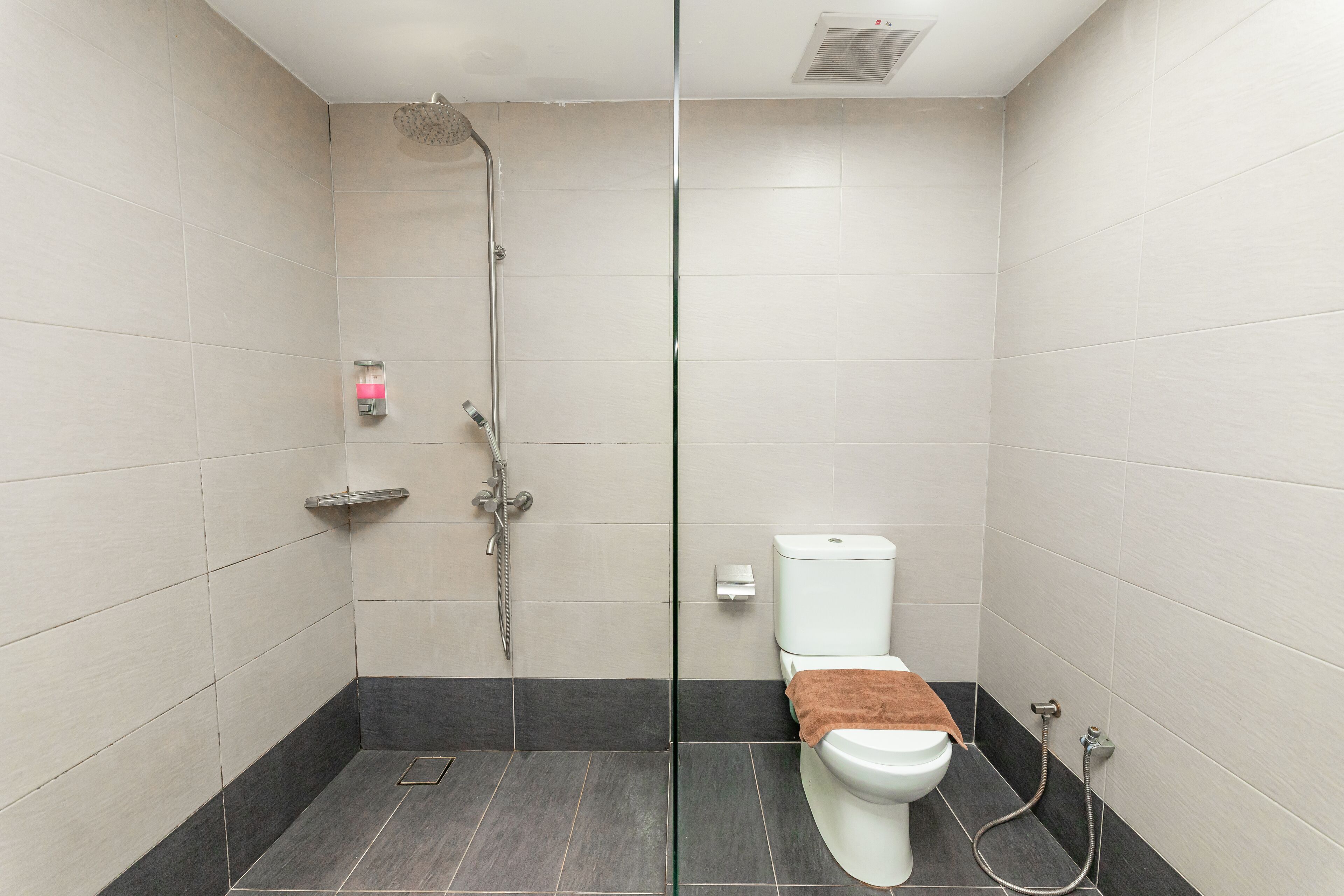 A modern bathroom with a shower, toilet, and a towel rack.