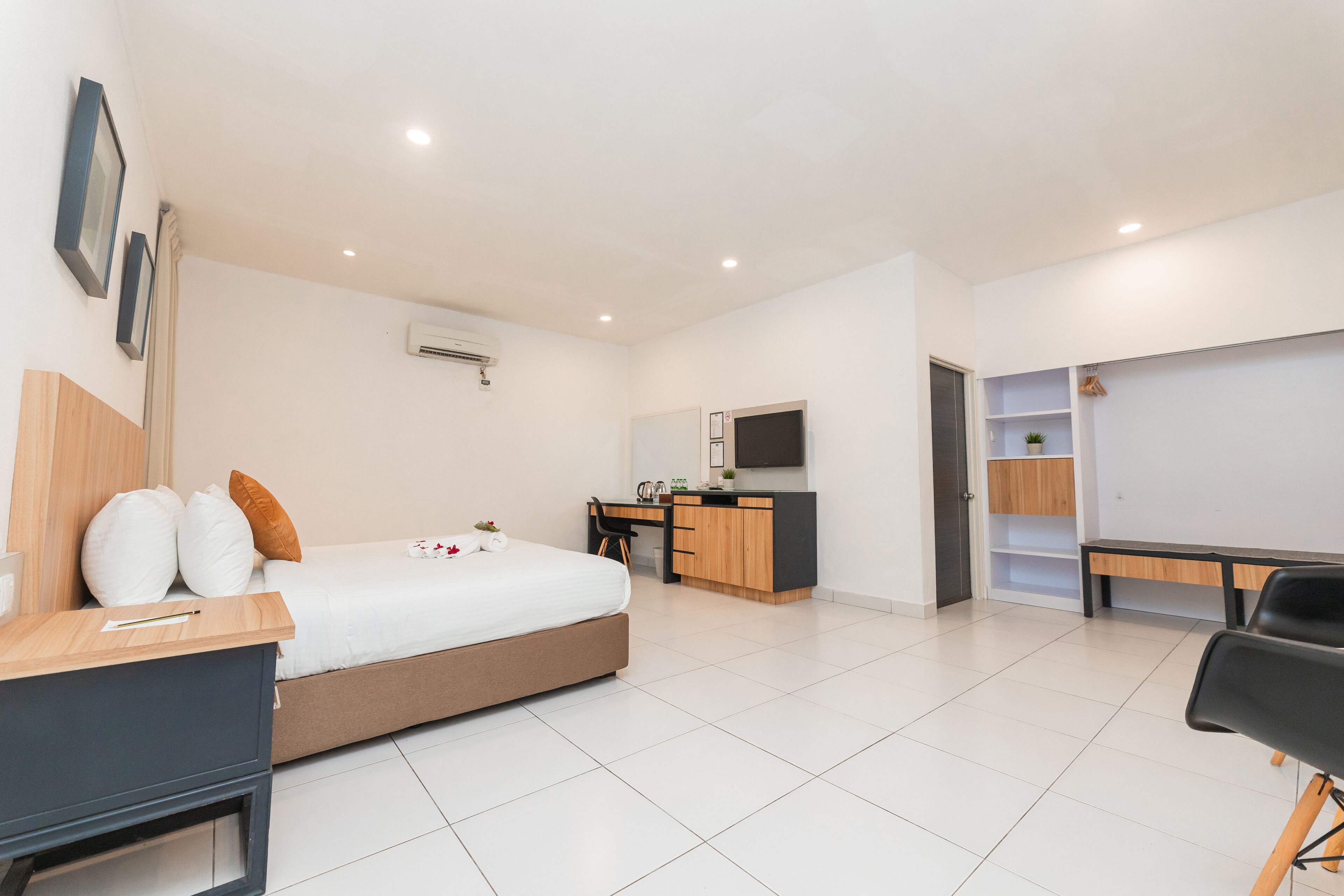A modern hotel room with a bed, desk, and wardrobe.