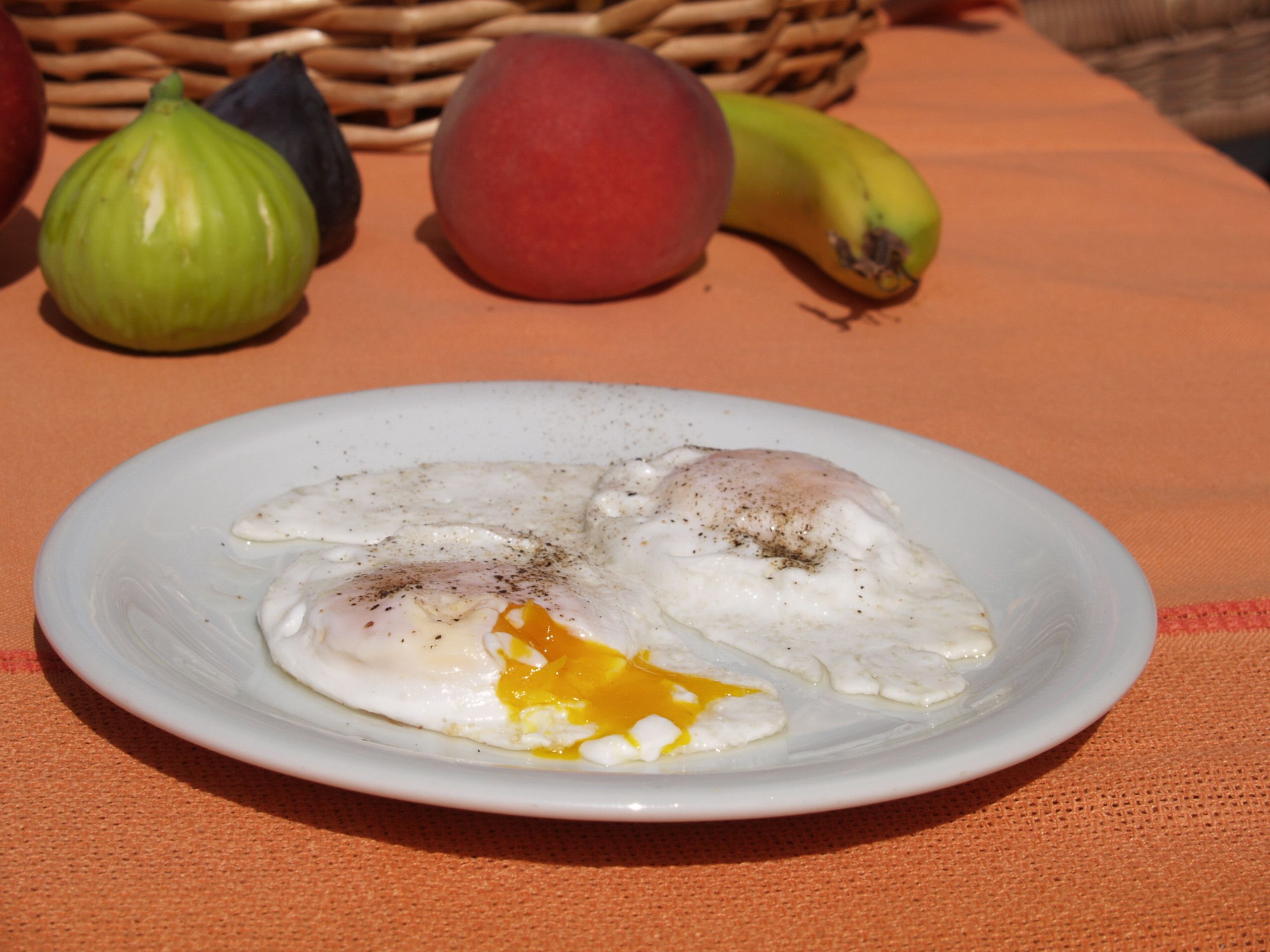 Un plato con dos huevos pochados sobre una servilleta naranja.
