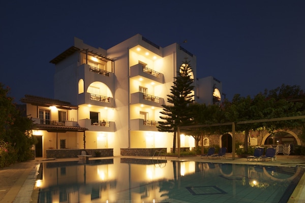 Una piscina al aire libre, sombrillas, sillones reclinables de piscina