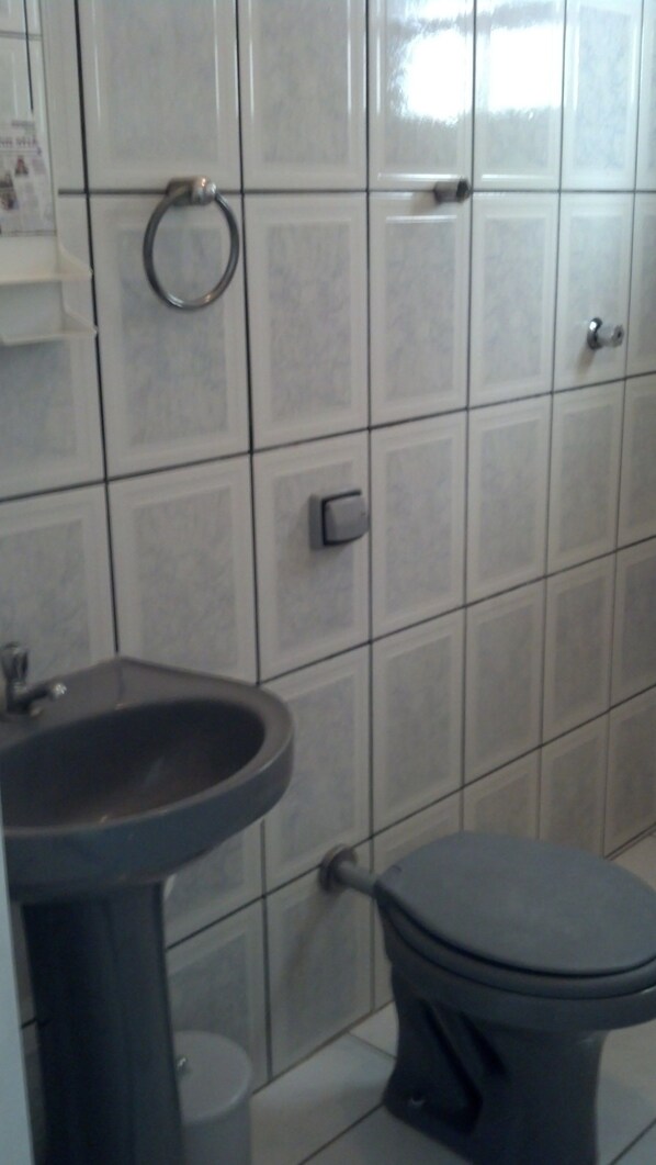 Un baño con lavamanos, inodoro y paredes de azulejos.