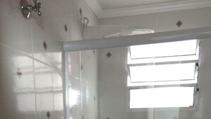 Un baño con cabina de ducha de vidrio, un lavabo blanco y un inodoro.