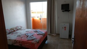 Un dormitorio con una cama, televisor y refrigerador.