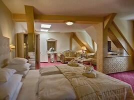 A hotel room with a large bed, a sitting area with a sofa and armchairs, a small table, and a mirror.