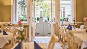 Un espace de restauration intérieur avec des tables et des chaises, une cloison centrale et de grandes fenêtres donnant sur l’extérieur.