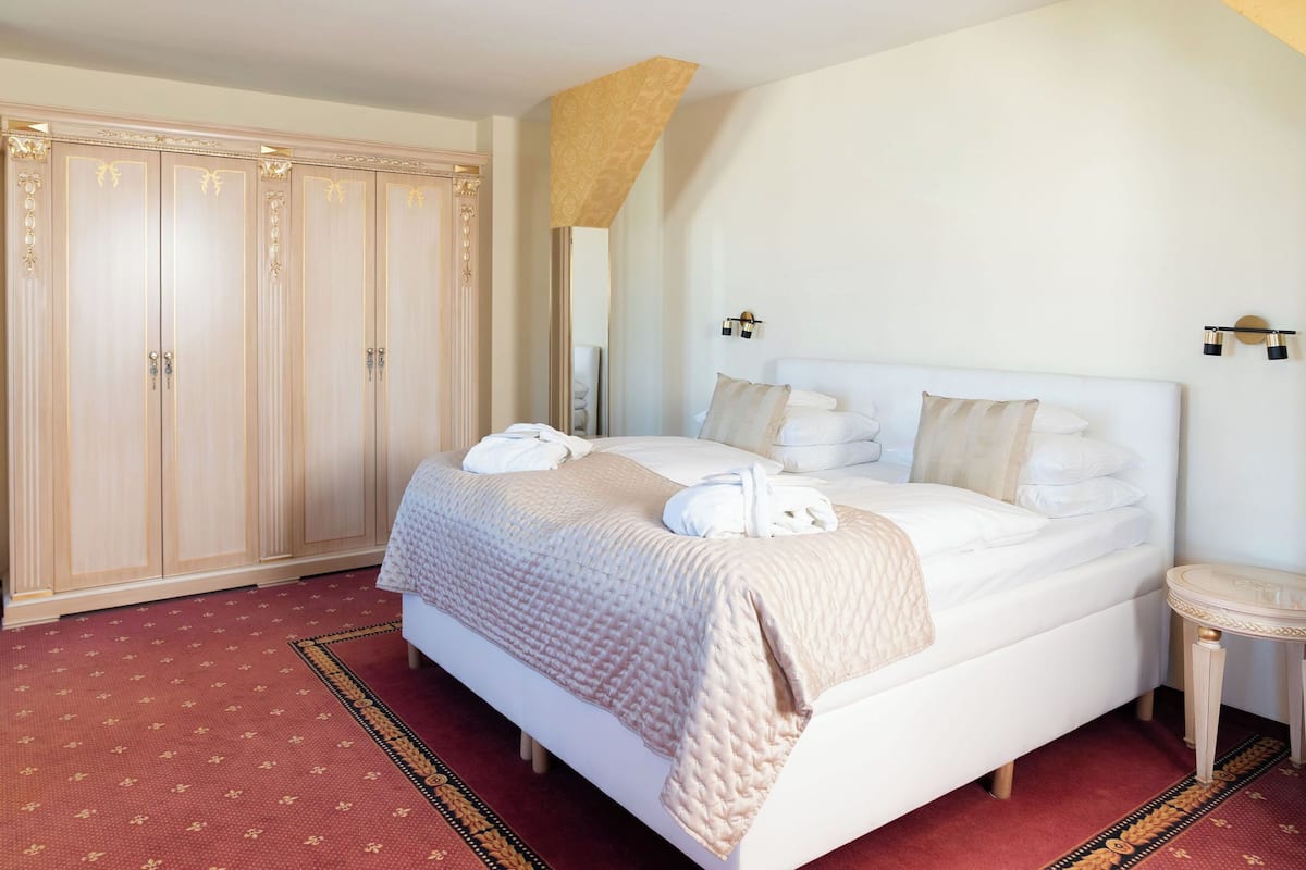 A hotel room with a large bed, a wardrobe, a bedside table, and a mirror.