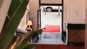 Un escalier menant à une voiture garée à l’extérieur, un tapis rouge et un luminaire suspendu.