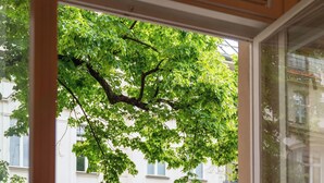 Un balcon avec une table, une chaise, un pot de fleurs et une vue sur un immeuble avec des fenêtres.