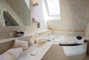 Un baño moderno con una bañera grande, un tocador con espejo y un ventanal que proporciona luz natural.