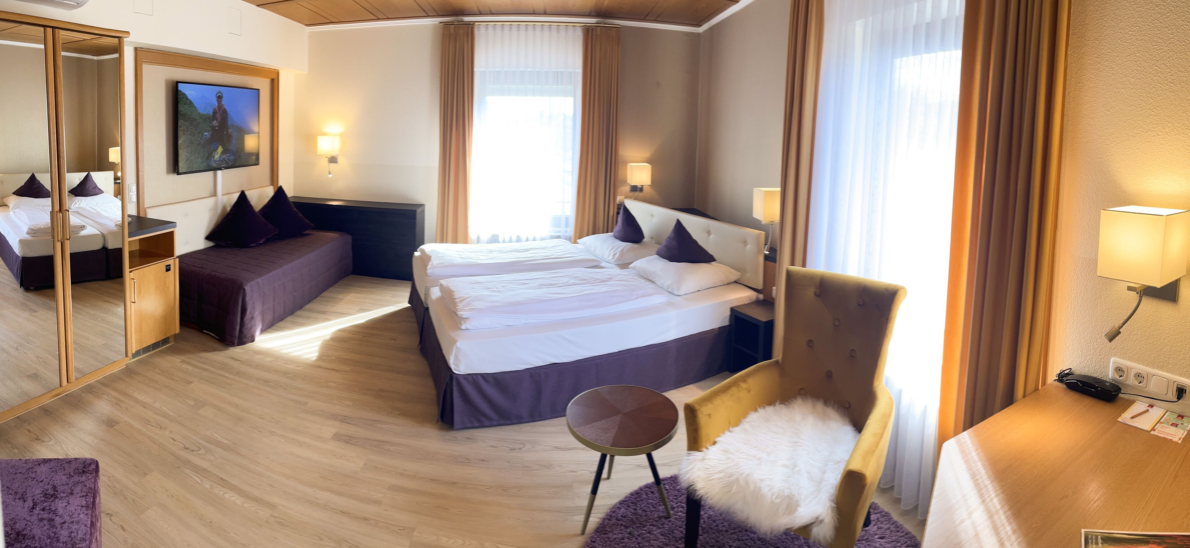 Una habitación de hotel con una cama grande, un sofá, una silla, un escritorio y una televisión.