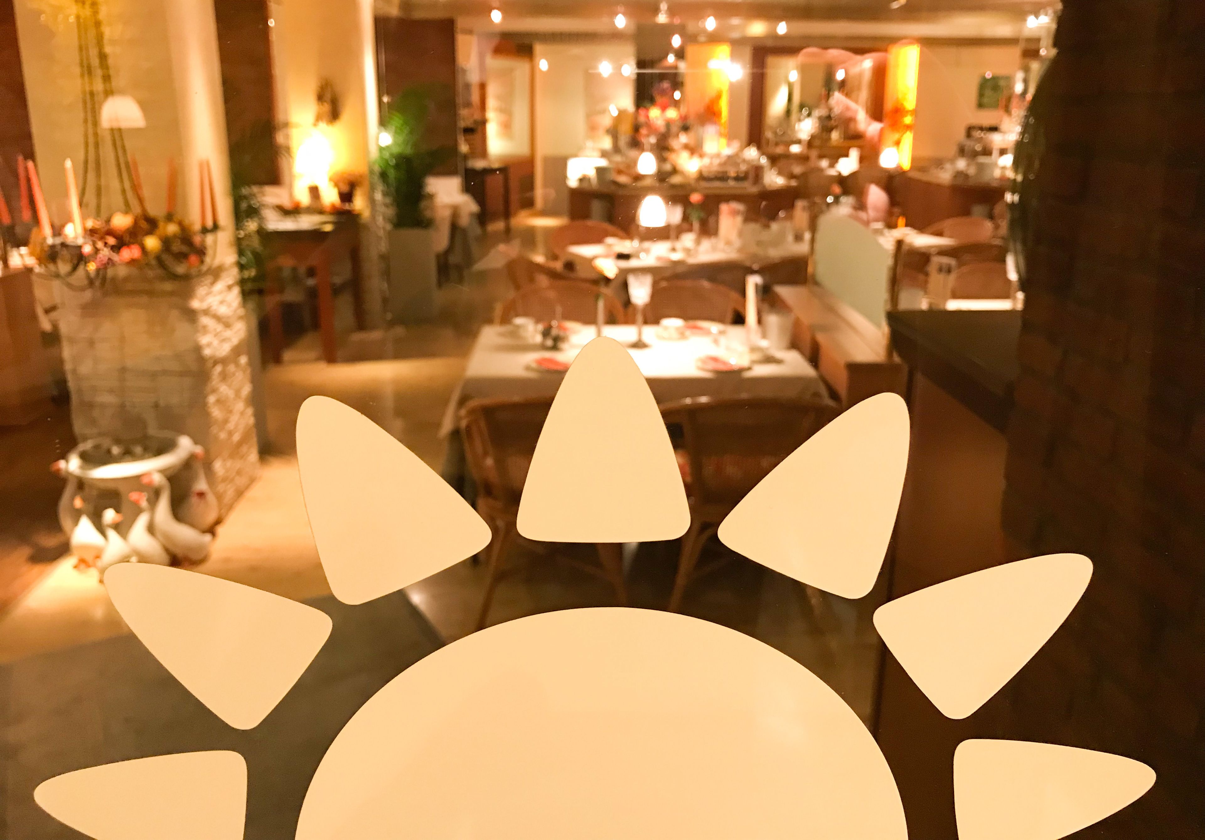 Un restaurante con varias mesas y sillas, iluminación cálida y un ambiente acogedor.