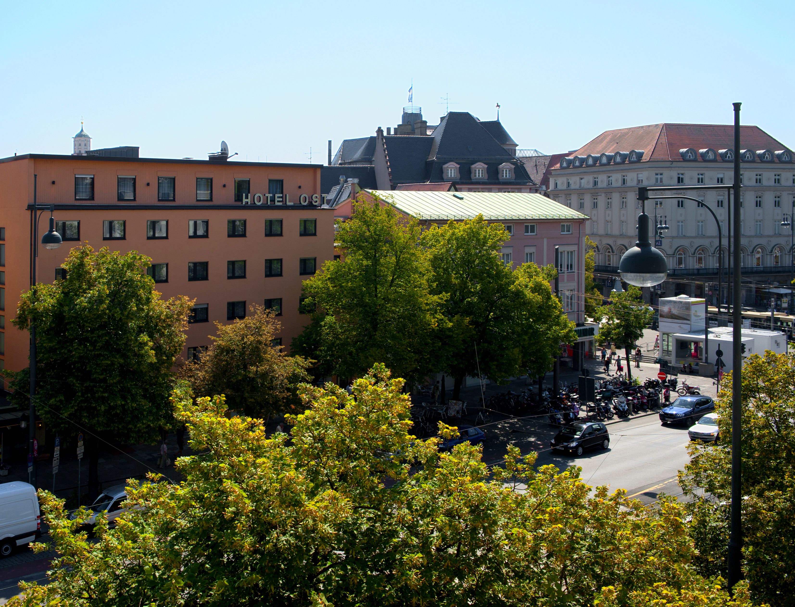 A hotel with a prominent sign, surrounded by trees and other buildings.