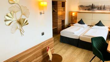 Een hotelkamer met een bed, twee nachtkastjes, een stoel, een klein rond tafeltje met een bord en een wandlamp.
