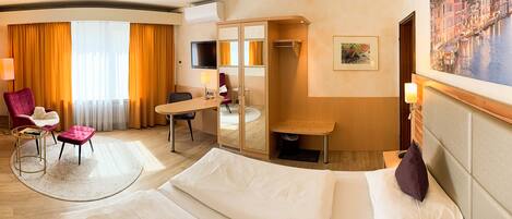 Una habitación de hotel con cama, escritorio, silla, televisión y un cuadro en la pared.
