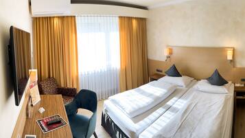 Habitación de hotel con dos camas, un escritorio con silla, televisión y un cuadro en la pared.