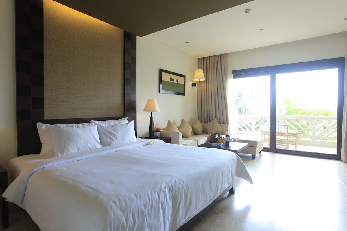 Une chambre d’hôtel avec un grand lit, un canapé, une table et une vue sur l’extérieur.