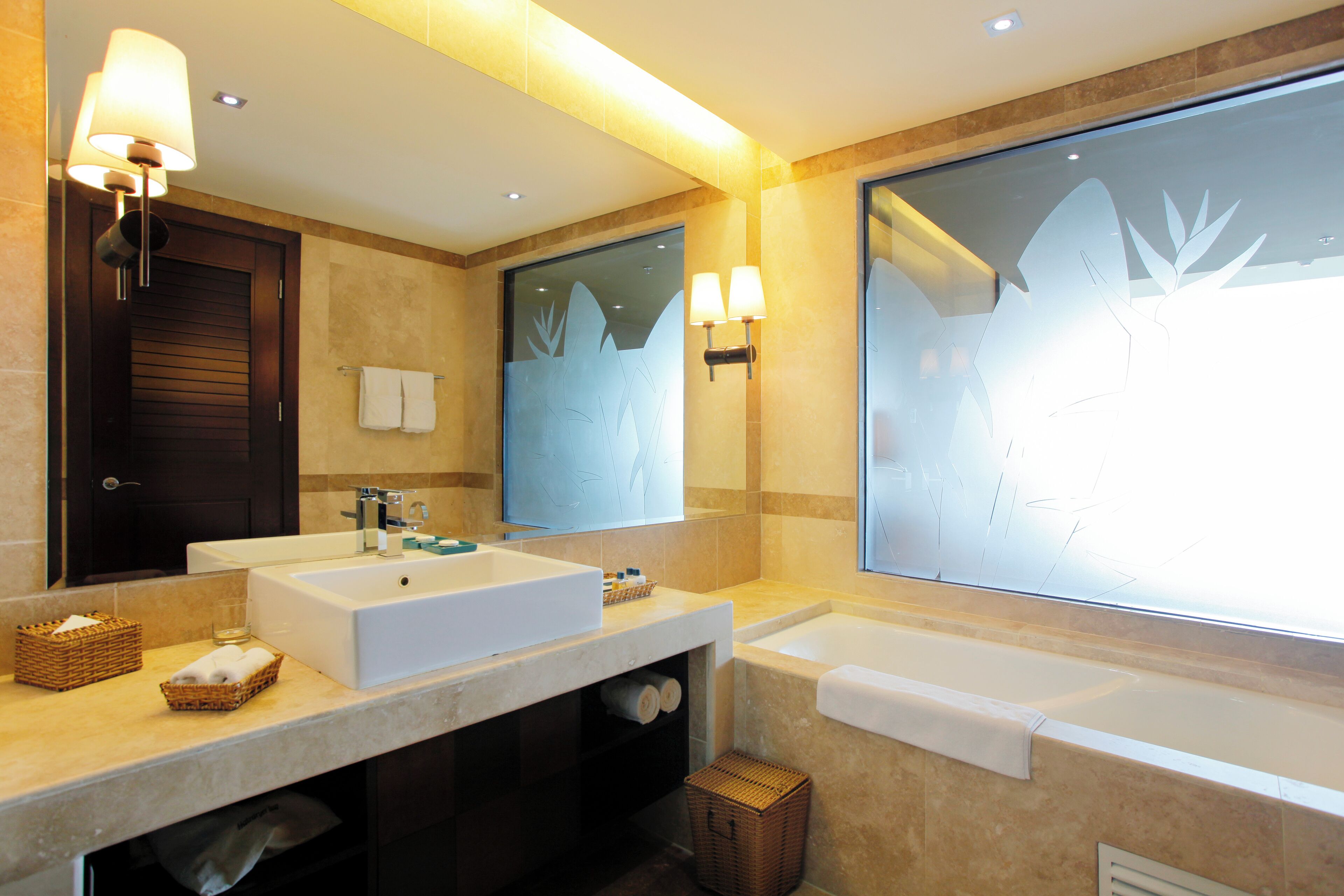 A modern bathroom with a large mirror, two sinks, a bathtub, and a window with frosted glass.