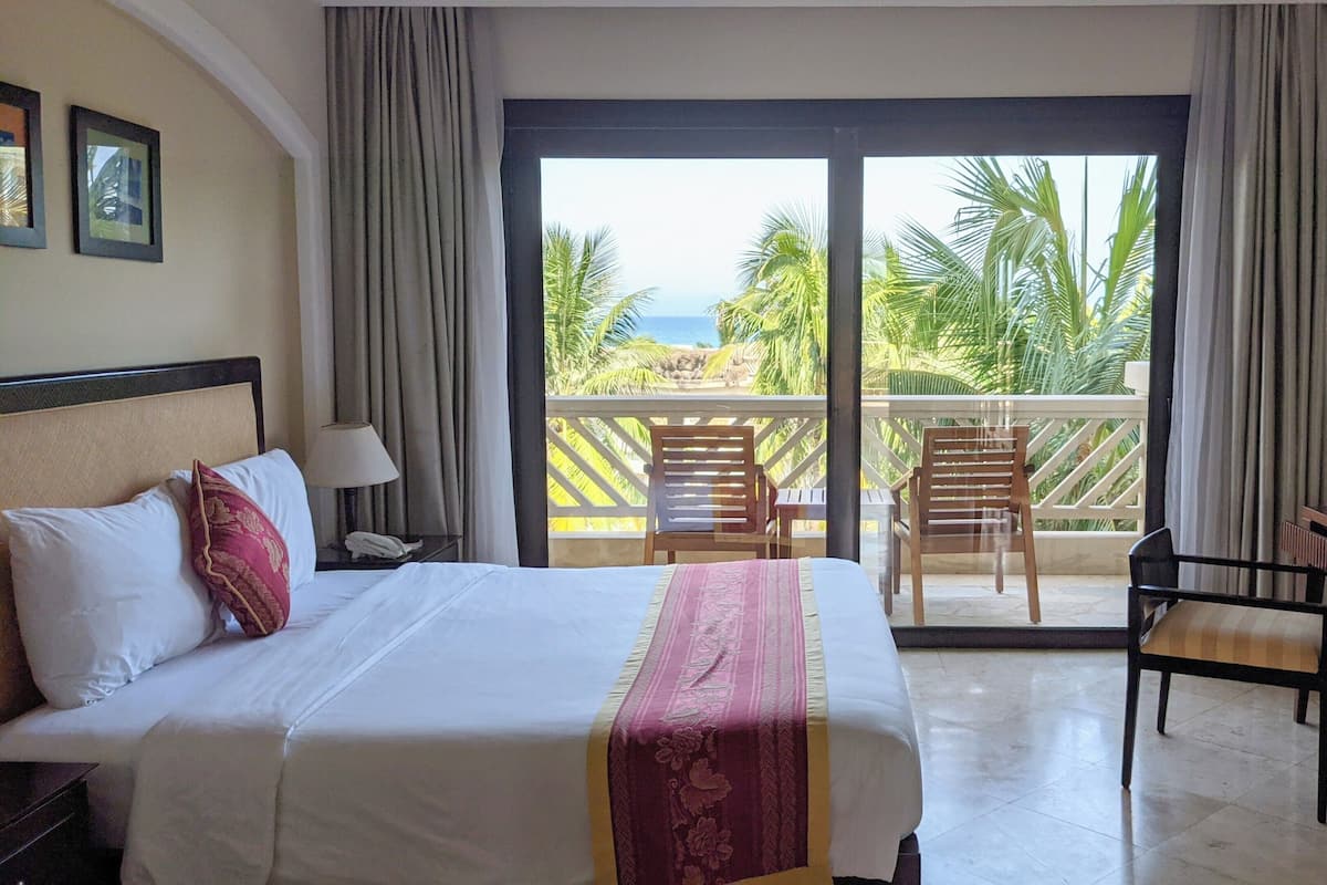 Une chambre d’hôtel avec un lit, un bureau et un balcon équipé de chaises.