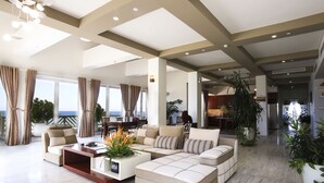 A spacious living area with a large sectional sofa, a coffee table, and a view of the ocean. - Olalani Resort and Condotel (Da Nang)