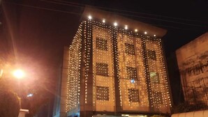 Un hotel con un letrero que dice 'The Habitable Hotel'. Cuenta con una fachada moderna con múltiples ventanas y está decorado con luces colgantes.