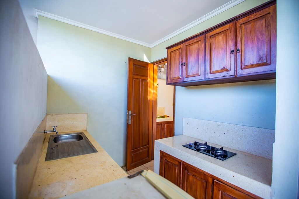 A compact kitchen with wooden cabinets, a built-in gas stove, and a small sink.
