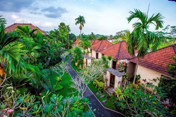 A residential area with houses having red-tiled roofs, surrounded by lush greenery and palm trees. - Villa Mandi Ubud (Ubud)