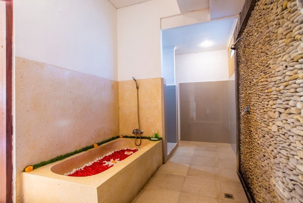 A bathroom with a bathtub, shower, and a pebble wall.