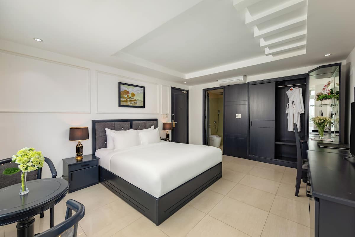 A modern hotel room with a large bed, bedside tables, a desk, and a chair.