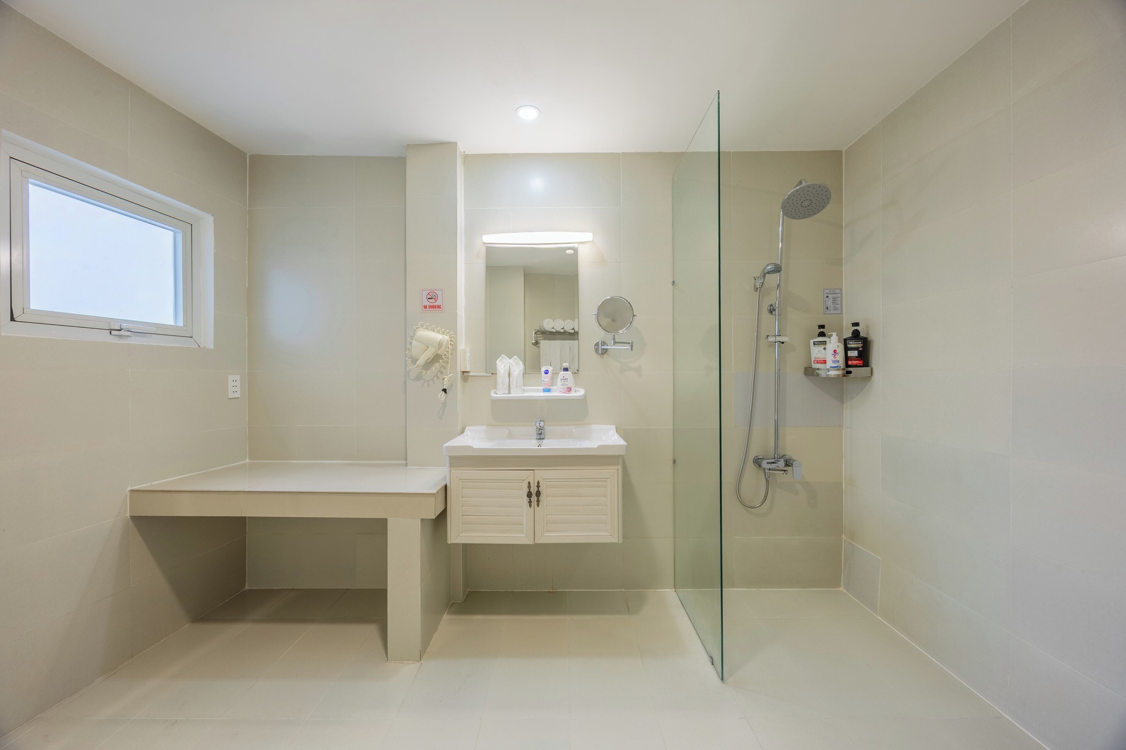 A modern bathroom with a glass-enclosed shower, a vanity with a mirror, and a window.