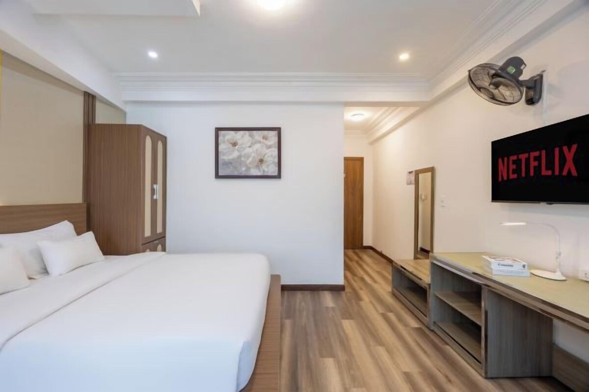 Camera d'albergo con un letto, una televisione a parete e un pavimento in legno.