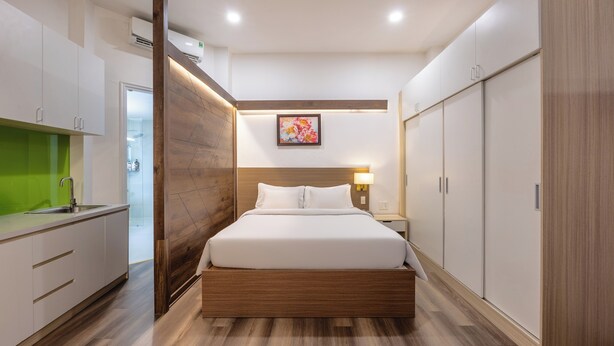 A modern hotel room with a wooden bed frame, a built-in desk, a green accent wall, and a large wardrobe. - A25 Hotel - 14 Pho Duc Chinh (Ho Chi Minh City)