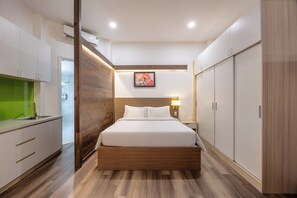 A modern hotel room with a wooden bed frame, a built-in desk, a green accent wall, and a large wardrobe. - A25 Hotel - 14 Pho Duc Chinh (Ho Chi Minh City)