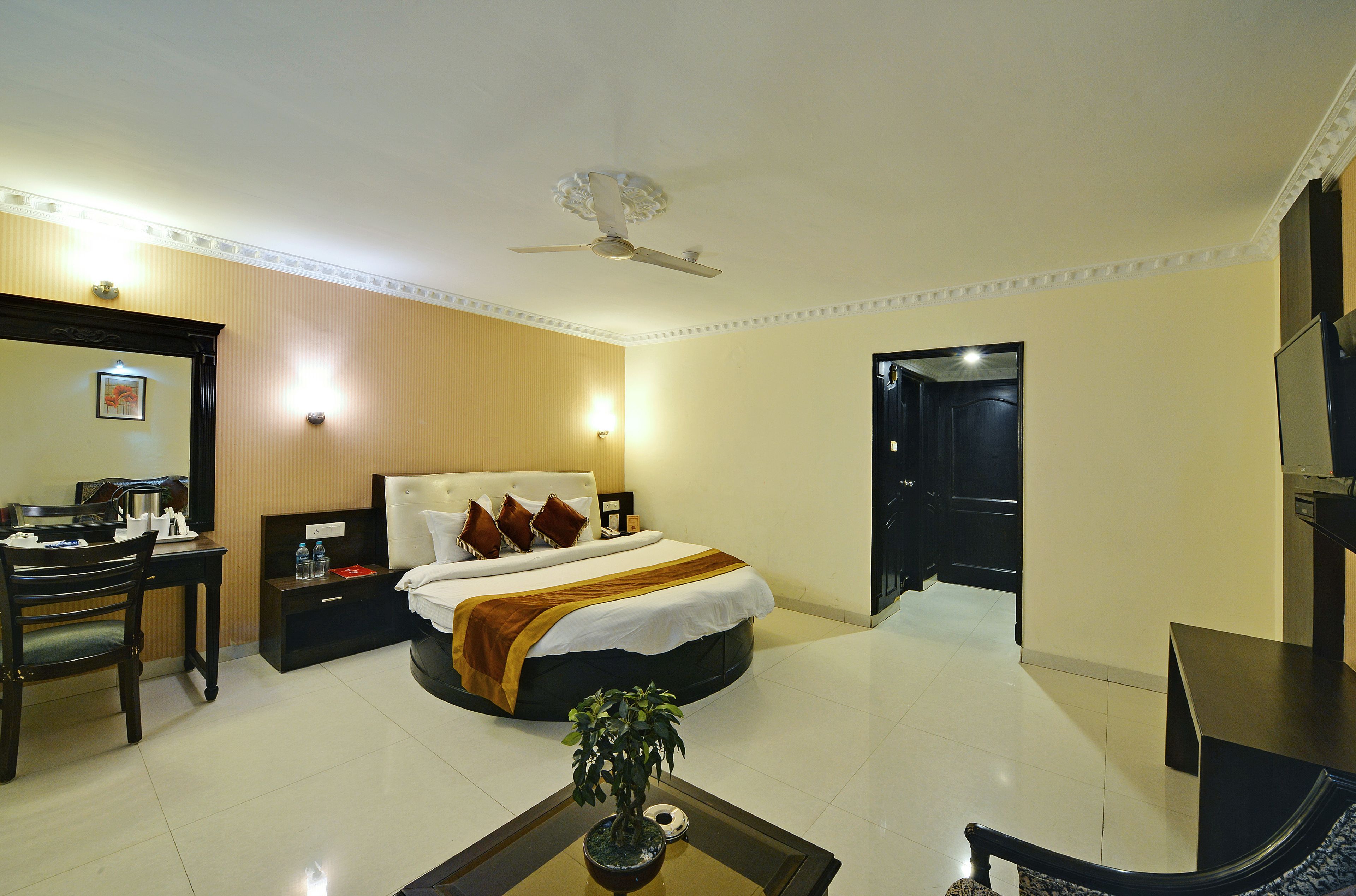 A hotel room with a bed, bedside table, desk, chair, and a ceiling fan.