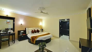 A hotel room with a bed, bedside table, desk, chair, and a ceiling fan.